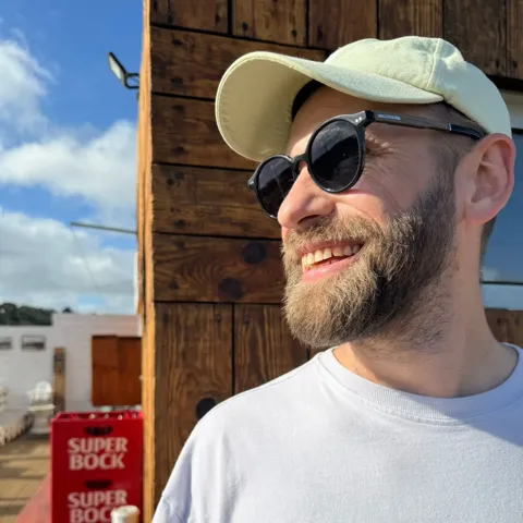 Porträt von Tim mit Kappe und Sonnenbrille.